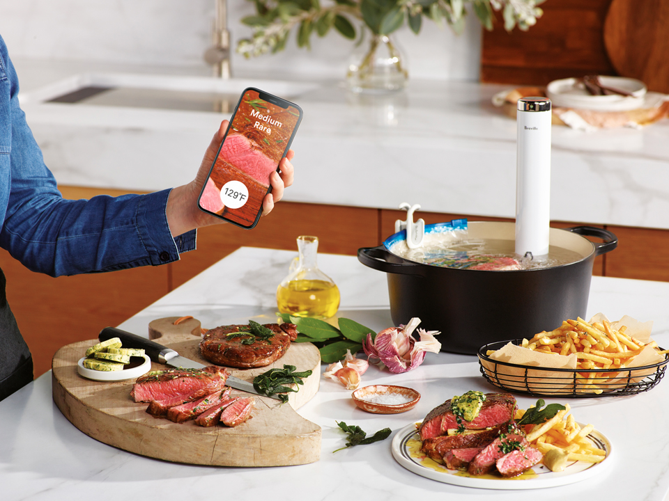 Phone displaying Medium Rare on screen and table with dishes and Joule Turbo Sous Vide