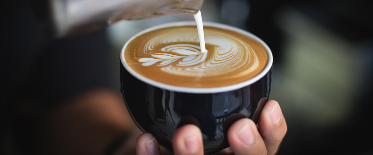Closeup of barista making beautiful latte art on a cappuccino.