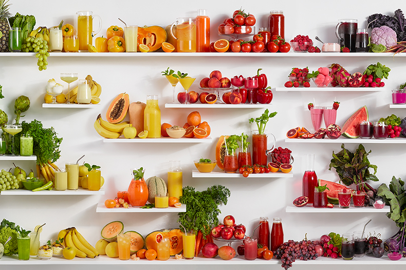 Display of a variety of fruits, vegetables and smoothies rearranged by color.